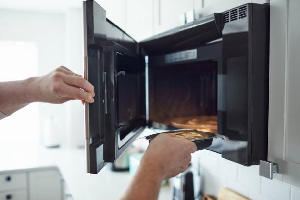 Unrecognizable male putting food into a microwave Unrecognizable male putting food into a microwave convenience food photos stock pictures, royalty-free photos & images