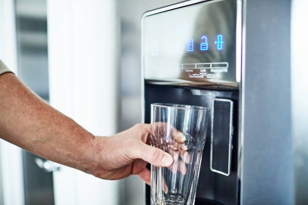 冷蔵庫の水ディスペンサーからガラスを充填する認識できない男 - water cooler ストックフォトと画像