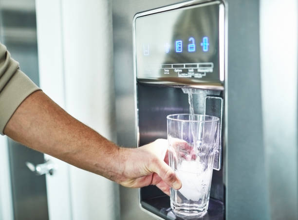 hombre irreconocible llenando vidrio del dispensador de agua del refrigerador - refrigeradora de agua fotografías e imágenes de stock