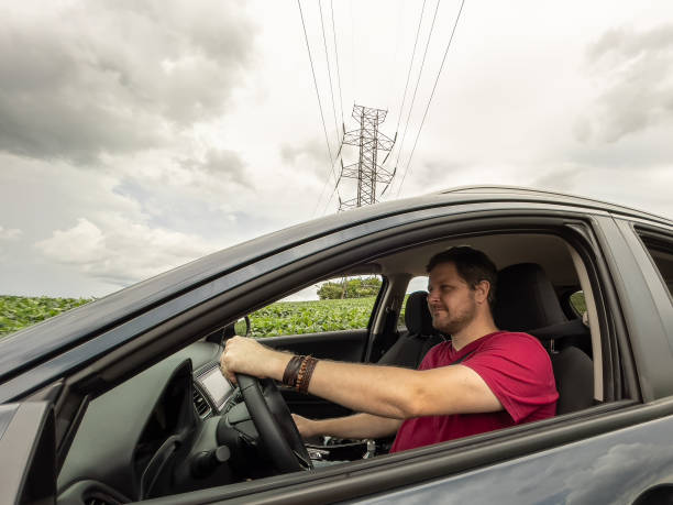 istock Man driving car on countryside with power lines on background 1300229792