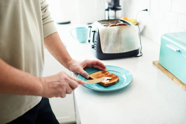 istock Unrecognizable man making toast for breakfast in brightly lit kitchen 1300230213