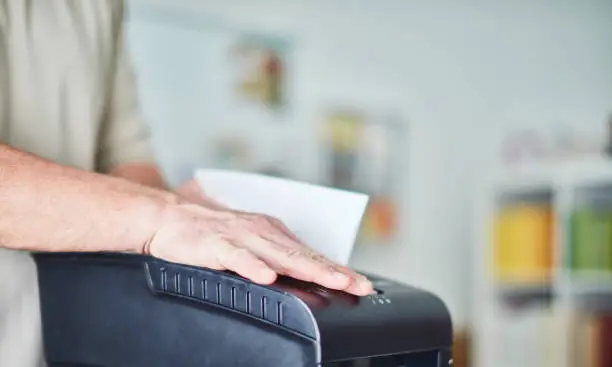 Unrecognizable male shredding paper in home office