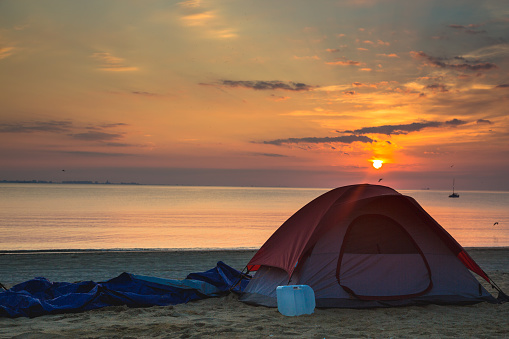 Camping on the beach with the sun rising right up over the tent