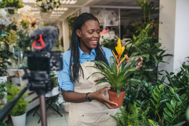 istock Young woman vlogging in greehouse 1300234097