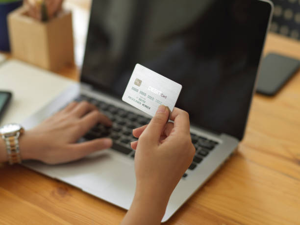 istock Female hand holding credit card while online paying on laptop 1300237798