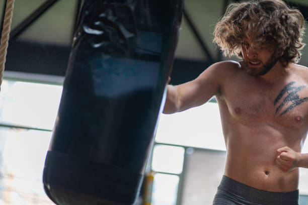 istock Latino man trains by hitting gym sandbag 1300238971