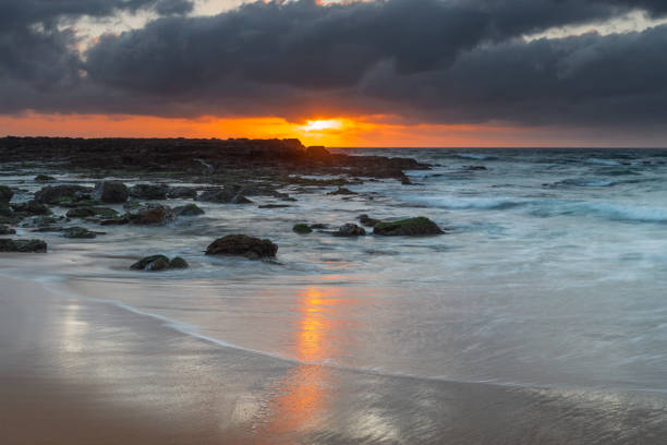 istock Grey clouds and rocky foreground overcast sunrise at the beach 1300241902