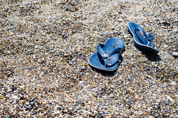 Blue flip flops on a pebble beach. Beach summer themes.