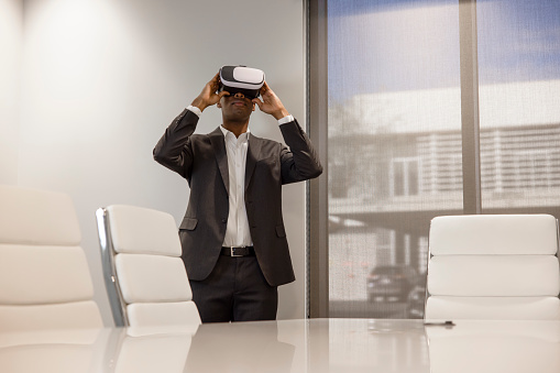 An African American Male office worker using a virtual reality headset to work.