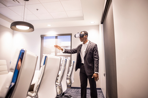 An African American Male office worker using a virtual reality headset to work.