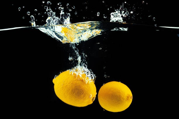 istock Lemons diving into the water with a splash against black background 1300255537