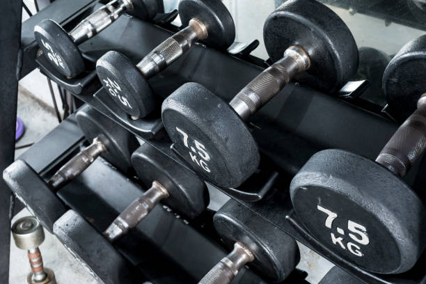 istock Various dumbbells with knurled handlebars and labeled weights on a tiered dumbbell rack at the gym. Weight training equipment. 1300258662