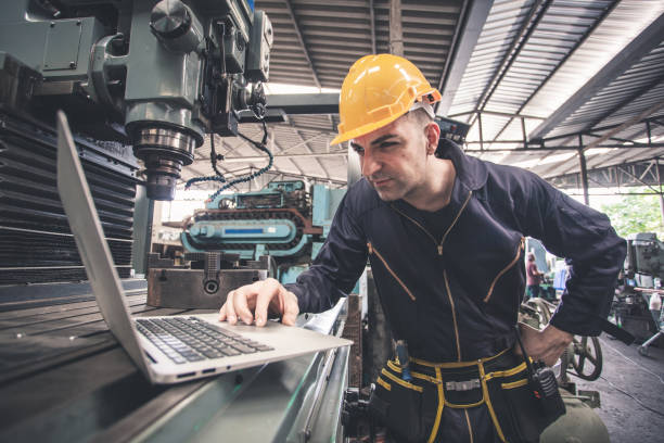 istock Factory worker in a hard hat is using a laptop in a factory. working 1300259334