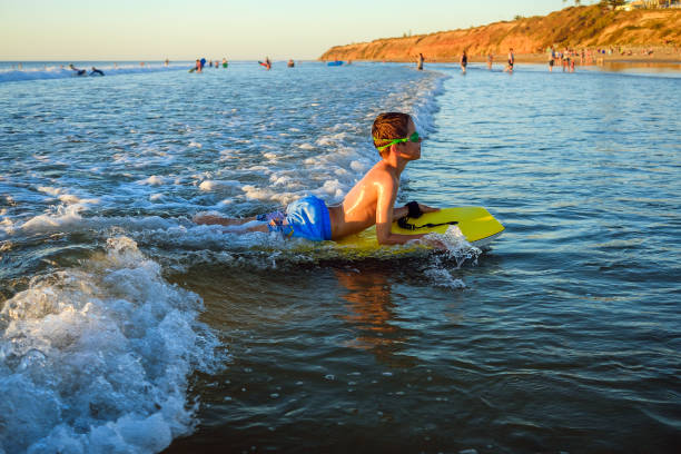 menino montando bodyboard enquanto usava óculos de natação na praia - bodysurfing - fotografias e filmes do acervo