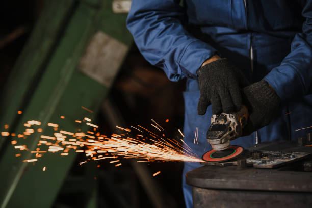 istock Young manual worker using grinder on metal in factory. Worker grinding in a workshop. Heavy industry factory, metalwork 1300263583