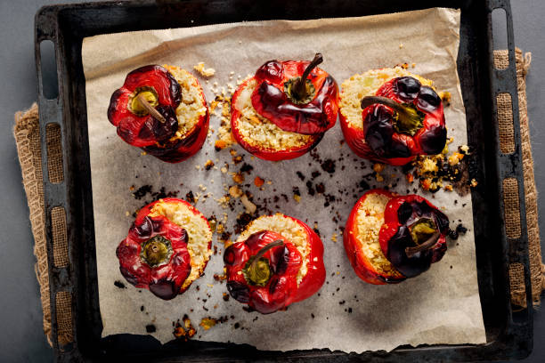 Roasted and Stuffed  Peppers. Overhead view of a baking tray full of delicious stuffed peppers fresh from the oven. They are red peppers that have been roasted and filled with a couscous and chickpea mix. Ideal for a vegan or vegetarian lunch or dinner. Colour, horizontal with some copy space. stuffed pepper stock pictures, royalty-free photos & images