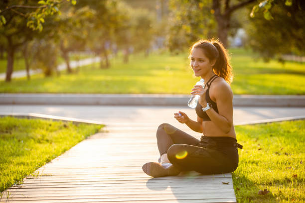 istock Young woman sitting on the path in the park, taking a break from jogging 1300266300