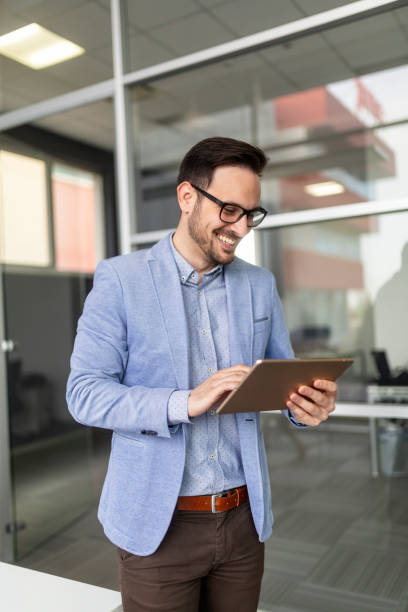 istock Smiling business man using digital tablet in the office 1300268317