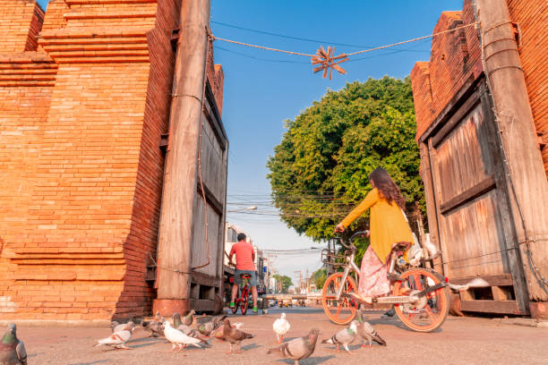 Chiang Mai / Thailand - February 20, 2019 : Tourists riding bikes through Thapae Gate, ancient symbol of old town Chiang Mai. Chiang Mai / Thailand - February 20, 2019 : Tourists can rent bikes provided by Chiang Mai municipality at Thapae Gate to explore the city. chiang mai province stock pictures, royalty-free photos & images