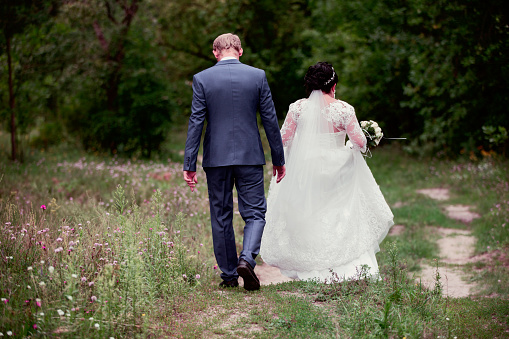 The bride and groom leave along the forest path.