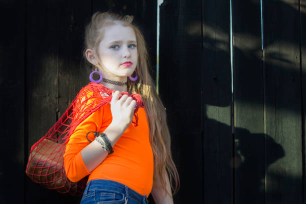A beautiful girl in bright clothes holds a string bag with a roll.
