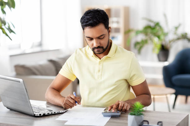 man with calculator and papers working at home - tax tax form financial advisor calculator imagens e fotografias de stock