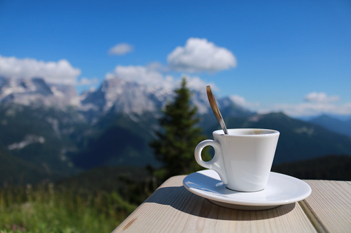 Close-up of a coffee cup with behind a beautiful view of the mountains from the refuge 5 lakes in Trentino, travel and landscapes in Italy