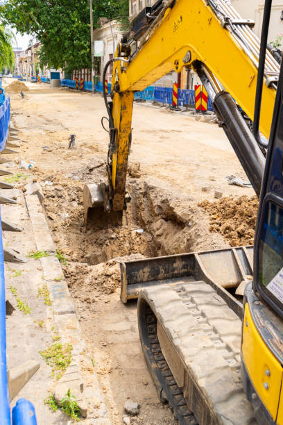 istock yellow excavator diggin a trench in the road 1300276403
