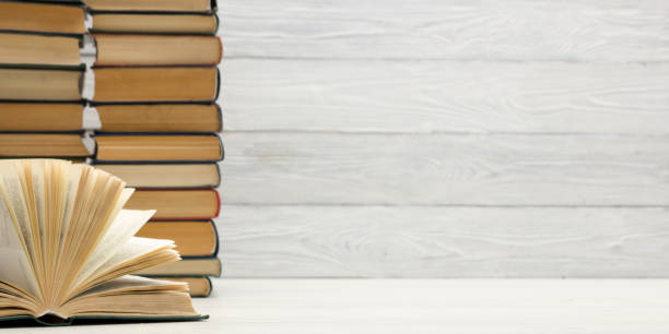istock Books on bookshelf in Library. Back to School education concept on colored abstract yellow background. Open hardback book stack in a raw on wooden desk table. 1300277545