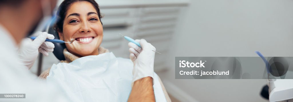 Woman getting dental treatment Dentist examining teeth of a female patient in dental clinic using dental tools. Happy woman getting dental treatment. Dentist Stock Photo