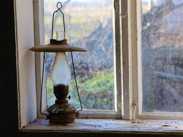 istock Old kerosene lamp on an old rustic retro and vintage window 1300279433
