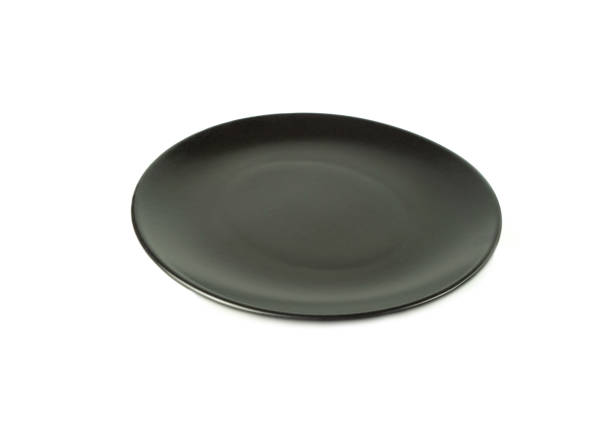 istock Empty black plate isolated on a white background. Use for home or restaurant, food design. Kitchen accessory. 1300280867