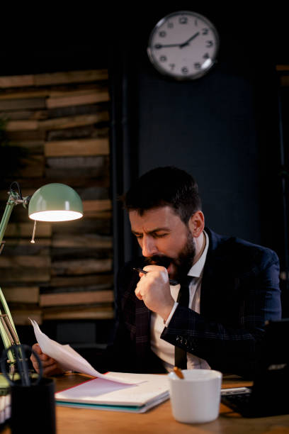 istock Tired man sitting at office desk drinking coffee. 1300282310