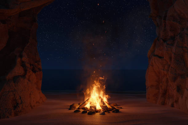 海と洞窟の前に火花や粒子と大きな焚き火の3dレンダリング - 岩屋 ストックフォトと画像