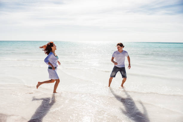istock couple playing together at the beach 1300282389