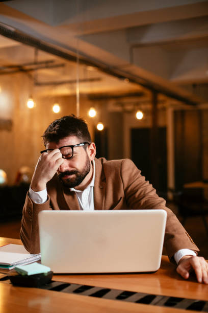 istock Tired man sitting at office desk drinking coffee. 1300282440