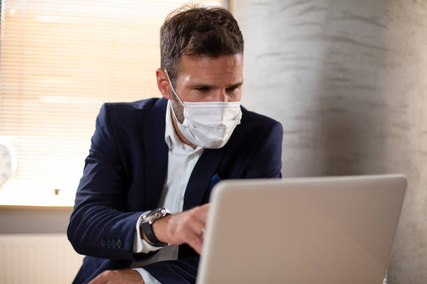 istock Young businessman with a mask working in his office on laptop. 1300285802