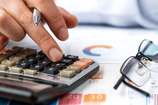 Close-up businessman analyzes graph chart and calculates.