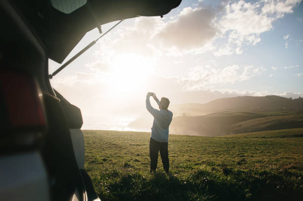 istock Young man taking a picture with a smart phone by his car 1300287191