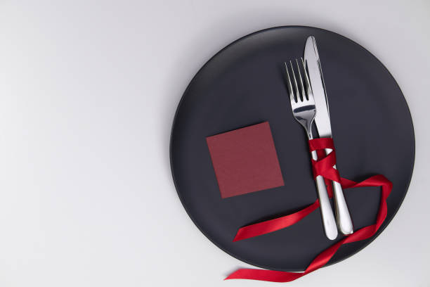 istock Dark Festive table setting with card. Red Ribbon matte gray plate. Valentine's Day. Place for inscriptions. Hearts on a white background. View from above. Greeting card with love Valentine's Day. 1300288083