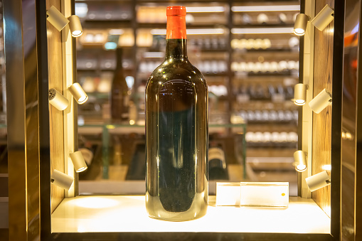 large wine bottle stand in a shining display case.