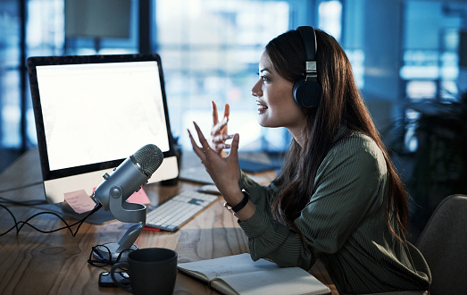 Shot of a woman doing a broadcast while sitting in an office at night