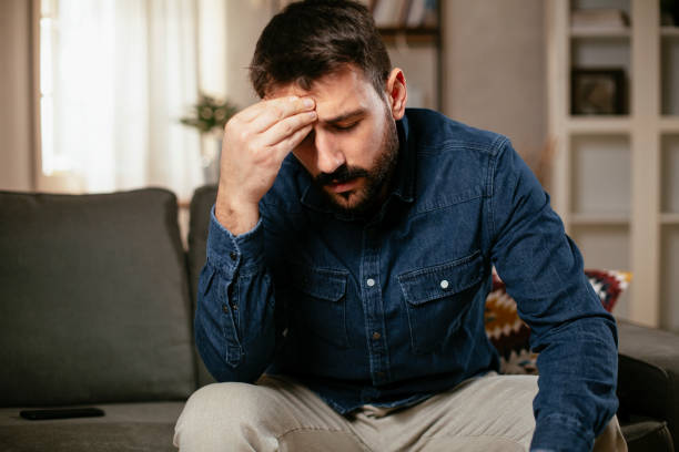 istock Young man sitting on sofa having fever. 1300289669