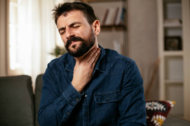 istock Young man sitting on sofa having fever. 1300289682