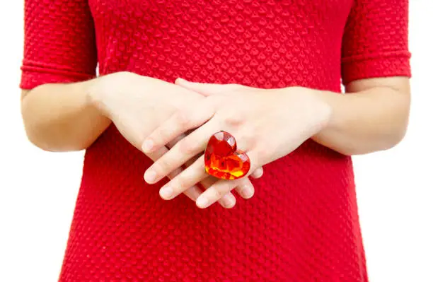 Photo of Woman in a red dress shows a ring with a huge ruby coloured heart-shaped plastic gem