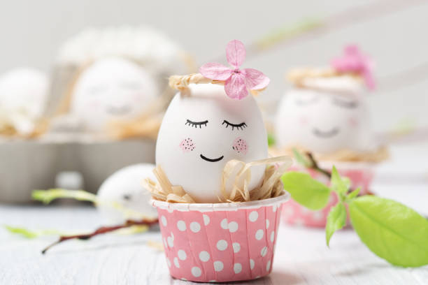 istock Easter holiday concept with cute handmade white eggs, tree branches, quail feathers and spring flowers on white wooden background. 1300291374
