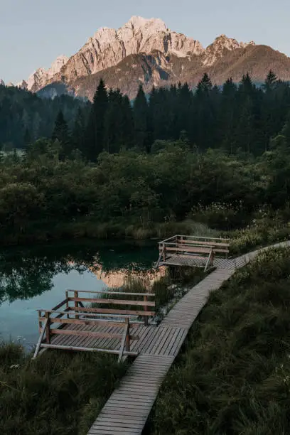 July 28, 2020 - Ratece, Slovenia: breathtaking sunrise in the mountains with a reflections on the small lake with viewing platforms in the nature reserve in Slovenia.