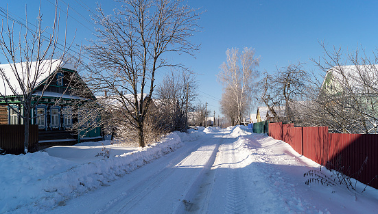 The Street in village with expensive on background blue sky at winter length of time. Beautiful rural landscape in Russia