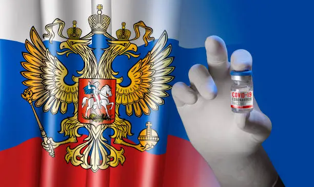 Photo of Hand holding vial ampoule vaccine for Corona Virus Covid-19 with russian Flag