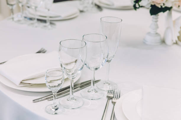 istock Fancy table set for dinner with napkin glasses in restaurant, luxury interior background. Wedding elegant banquet decoration and items for food arranged by catering service on white tablecloth table 1300300516